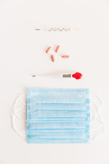Medical protective mask with a thermometer on white background with pills. A disposable surgical face mask. Healthcare and medical concept.
Prevention of the Covid-19 pandemic virus. Quarantine.