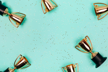 Frame made of winner cups on a pastel blue background with copy space. Flat lay style.