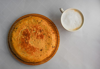 Spanish potato omelette next to a cup of cappuccino. Typical Spanish breakfast at a bar. Top View. Served on top of a wooden board. Space for text. 