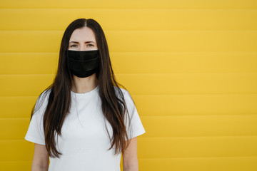 Woman wearing face mask because of Air pollution or virus epidemic in the city. Оn a yellow background. Corona virus concept. Close-up