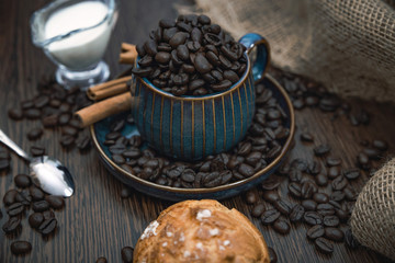 cup full of coffee beans with bun, milk and canvas on brown table