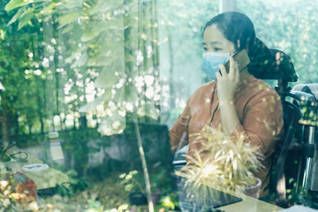 Woman wearing face mask and calling to people, working on computer at home. Covid-19 Pandemic (Coronavirus).