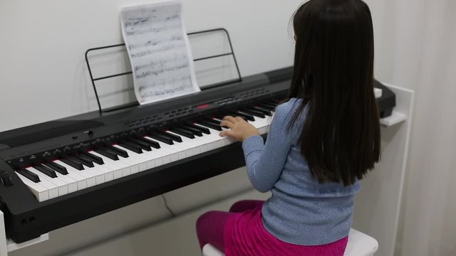 Little girl studying to play the piano at home. Preschool child having fun with learning to play music instrument. Education, skills concept. quick video