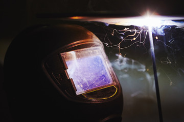 Man in protective mask welding metal construction.