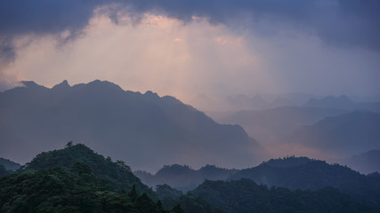 Fototapeta na wymiar A stunning sunrise over the mountains in China with golden and blue/purple colours, covered by forest and jungles 