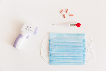 Medical protective mask with a thermometer on white background with pills. A disposable surgical face mask. Healthcare and medical concept.
Prevention of the Covid-19 pandemic virus. Quarantine.