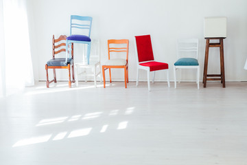 lots of different chairs in the interior of an empty white room