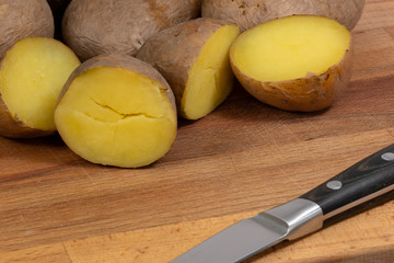 boiled potatoes on wooden background 
and a knife