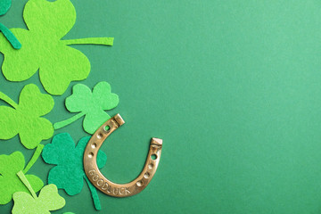 Flat lay composition with clover leaves and horseshoe on green background, space for text. St....