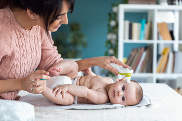 Mother measuring temperature of her baby boy with infrared thermometer at home.