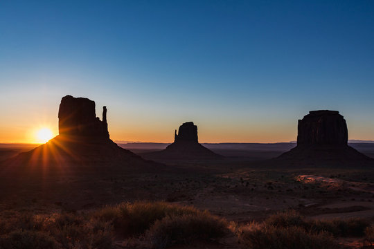 The sun rising on the background of The Mittens and Merrick Butte from John Wayne's Point the Oljato Navajo Monument Valley, Arizona USA