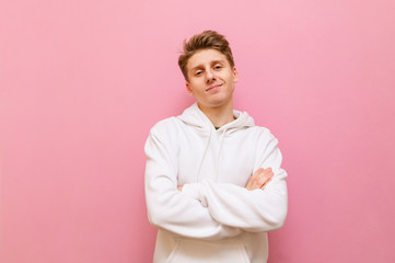 Portrait handsome blond boy in white casual clothes isolated on a pink background, looks into the...