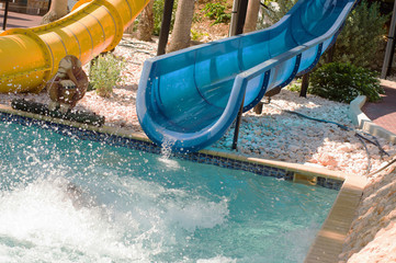 End of blue water slide in swimming pool with splashing water