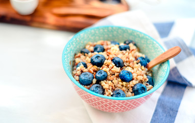 Bowl of buckwheat porridge with blueberry on vintage table top view in flat lay style. Hot breakfast and homemade food