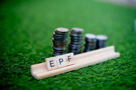 Wooden blocks spelling EPF with a stack of coins growing in size set on grass
