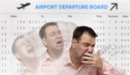 A man is coughs to his hand, on a background a board of departing aircrafts. A sick passenger sneezes bacilli and viruses around himself.