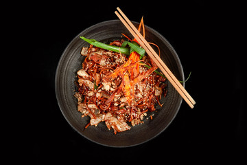 Noodles in a Black Bowl with Cashew Cabbage Fried Onions Sesame and Carrots with Chopsticks Side View                         