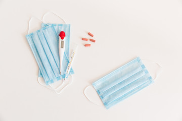 Medical protective mask with a thermometer on white background with pills. A disposable surgical face mask. Healthcare and medical concept.
Prevention of the Covid-19 pandemic virus. Quarantine.