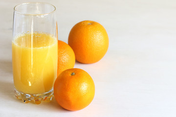 glass with orange juice on a background of oranges on the table front view. freshly squeezed natural drink