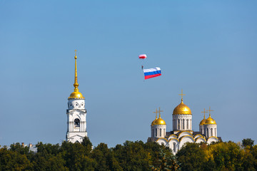 Fototapeta na wymiar Skydiver with the Russian flag in the sky over the Assumption Cathedral in Vladimir city, Russia.