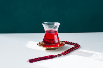 Turkish tea in a glass, muslim beads on a white background.