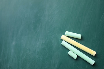 Pieces of color chalk on greenboard, flat lay. Space for text
