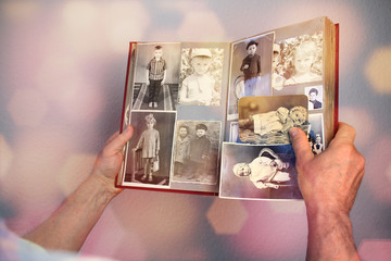 man’s hands of an old man holding an old retro album with vintage monochrome photographs in sepia color, the concept of genialogy, memory of ancestors, family ties, childhood memories