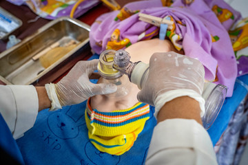 Medical professionals in West Java, Indonesia, practice nenatal resuscitation training techniques with a breathing device and a baby mannequin.