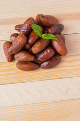 Vertical photo pile of dried dates palm fruits with mint leaf, top view