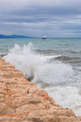 Wave hits the rock. Big waves in the sea. Ship in the sea
