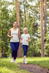 Fototapeta premium running sporty mother and daughter. woman and child jogging in a park. outdoor sports and fitness family.