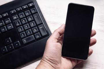 hand holding a smartphone and a keyboard