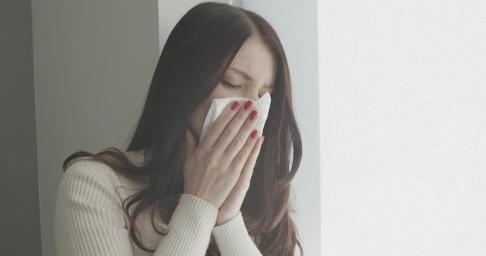 Close up portrait of beautiful woman sneezes and coughs, uses tissue, rubs nose, has bad cold, isolated over white background. Low spirited desperate woman suffers from cold and running nose.