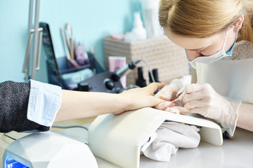 beautician making hardware manicure. woman hands receiving nail procedure in beauty salon.