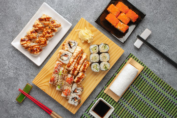 Set of sushi and maki with soy sauce over stone background. Top view