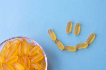 A lot of soft jelly capsules with fish oil as a source of Omega 3 in a bowl on blue background....