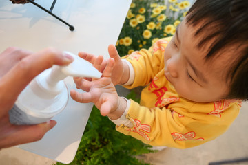 Asian cute baby using hand sanitizer