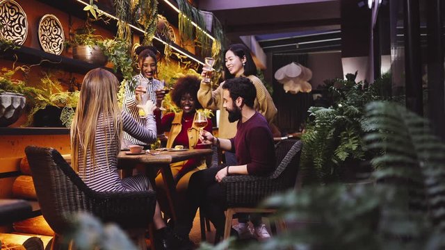  A group of friends from various ethnic groups enjoy happily and toast in a restaurant and bar with a very careful and elegant decoration
