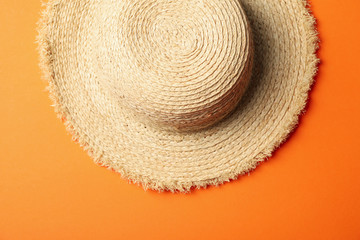 Fototapeta na wymiar Straw hat on orange background, top view