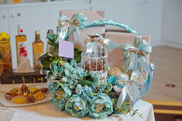 Basket with sweets stands on the table . Grey box . Bird and Cage . Engagement aqua color basket .