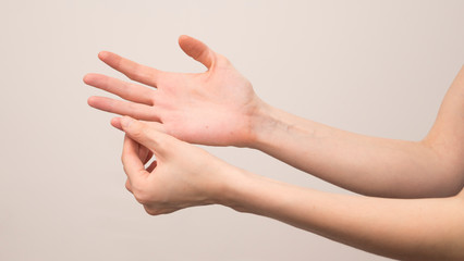 Close-up of female hands holding her painful wrist caused by prolonged work on a computer, laptop. Carpal tunnel syndrome, arthritis, neurological disease.