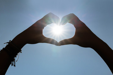 Fototapeta premium 2 hands that form a heart around the sun