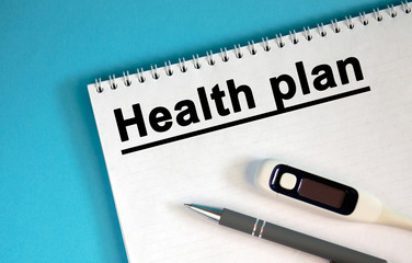 HEALTH PLAN - text on a notepad. Lie a pen and a medical thermometer