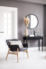 Modern living room interior with stucco molding on the walls with a Scandinavian-style armchair, console, mirror and coffee table.