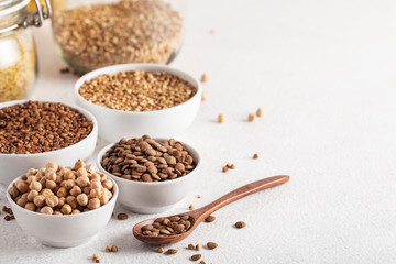 cereals buckwheat chickpeas lentils on a white table side view assorted wooden spoon