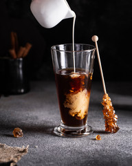 cold coffee with ice and cream in a long glass on the table summer drink