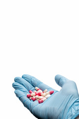 Hand in a medical glove holding pills on a white background. Flu medicine. Infection treatment. Closeup. Isolated