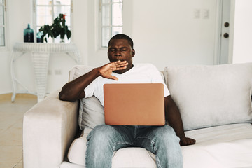 A man of African appearance at home in front of a laptop relaxing