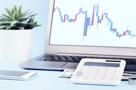 Finance stock graph on laptop with calculator and stack of money