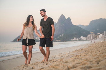 Young couple walking down Ipanema beach in Rio de Janeiro
